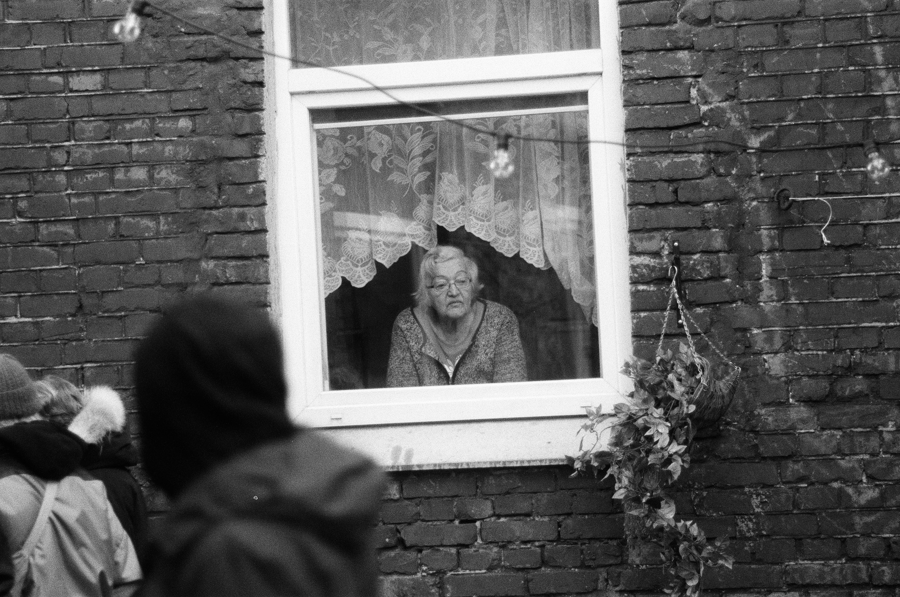 Elder standing beside window